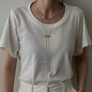 Detailed close-up of double layered minimalist gold chain necklace on a model