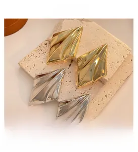 Macro view of geometric diamond stud earrings in polished gold and silver finishes