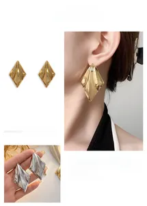 Detailed view of high-shine metallic geometric diamond stud earrings in gold and silver