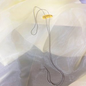 Detail of adjustable silver snake chain necklace with a polished gold curved slider