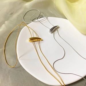 Detailed view of polished gold and silver long snake chain necklaces on a white tray
