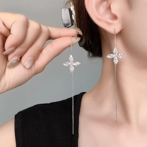 Detailed close-up of clover tassel chain earring with shimmering zircons on model