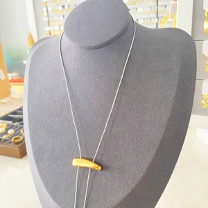 Close-up of minimalist silver snake chain with golden irregular metal pendant on mannequin