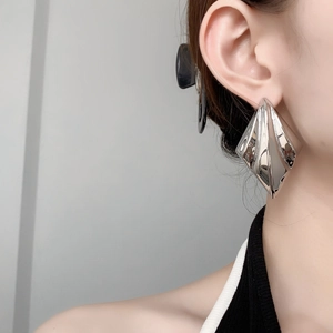 Macro shot of large silver geometric rhombus earrings with polished mirror finish on model