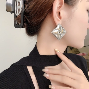 Silver geometric rhombus earrings with spiral texture shown on model side profile