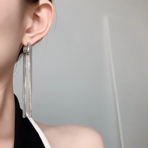 Detail of silver long chain tassel earrings with minimalist U-shaped drop design