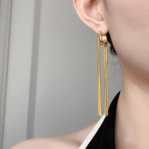 Close-up of 18K gold plated U-shaped earrings with long delicate chain tassels on model