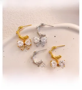 Macro shot of C-shaped bow earrings with sparkling blue heart crystals in gold and silver