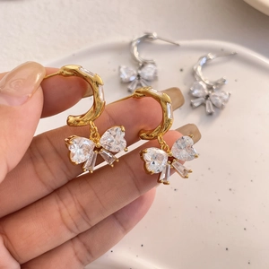 Detailed close-up of bow knot drop earrings featuring sparkling crystals in gold and silver