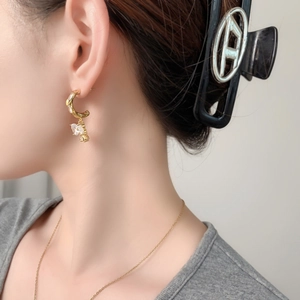 Elegant gold hook earrings with blue crystal bow and clear zircon drops on model