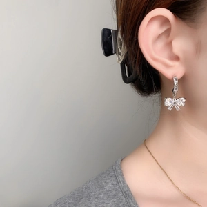 Elegant silver bow earrings with sparkling blue crystals on a model for a chic look