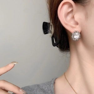 Oval zircon stud earrings with silver sunflower design worn by a female model