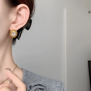 Detailed close-up of a sunflower stud earring featuring a brilliant white zircon center