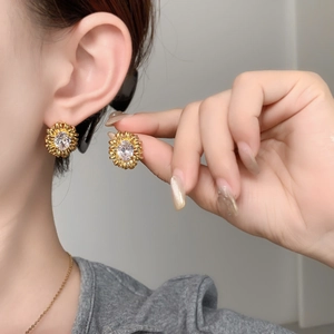 Close-up of sunflower stud earrings with oval white zircon and gold plated petals