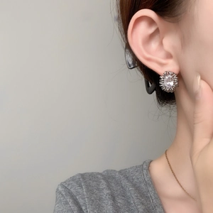Close-up of model wearing oval zircon sunflower stud earrings in silver finish