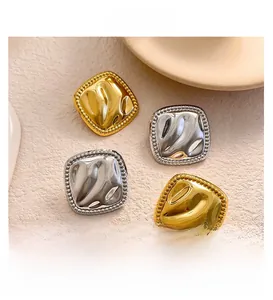 Macro detail of square textured gold and silver earrings with hammered finish and beaded edges