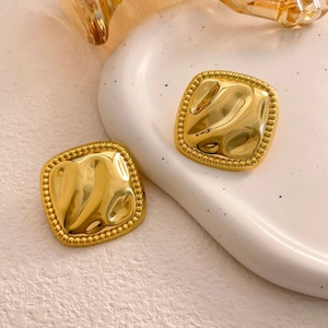 Close-up of gold square stud earrings with wrinkled texture and beaded edges