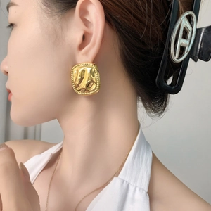 Statement oversized gold square studs with hammered texture and beaded edges on model