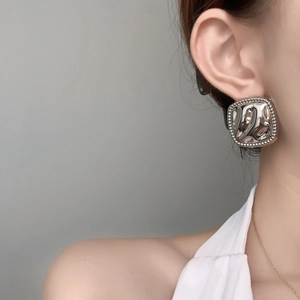 Macro detail of geometric silver square stud earring with textured fluid finish