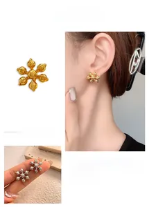 Détail de boucles d'oreilles fleurs à six pétales en or et argent au fini métal brillant