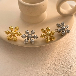 Vue macro des boucles d'oreilles fleur à six pétales en or et argent avec détails torsadés