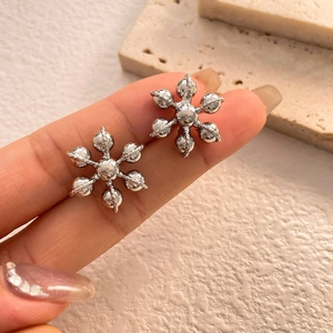 Boucles d'oreilles flocon de neige en argent poli avec pétales perlés tenus en main
