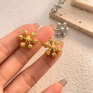 Gros plan de boucles d'oreilles dorées en forme de fleur avec finition polie