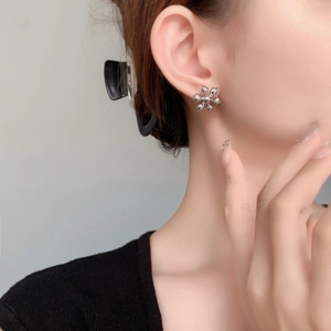 Élégantes boucles d'oreilles fleur 3D argentées avec finition brillante sur un mannequin