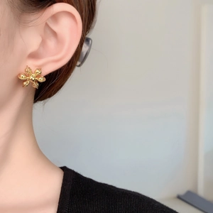 Gros plan d'une boucle d'oreille fleur dorée portée par un mannequin en gros plan