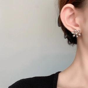Gros plan d'une boucle d'oreille fleurie en argent avec un motif délicat à six pétales