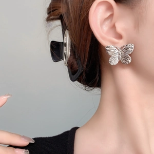 Elegante silberne Schmetterlings-Ohrstecker mit strukturierter Optik an einem Model