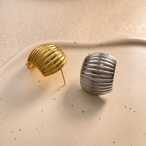 Close-up of C-shaped hoop earrings with unique vertical wavy textures in gold and silver