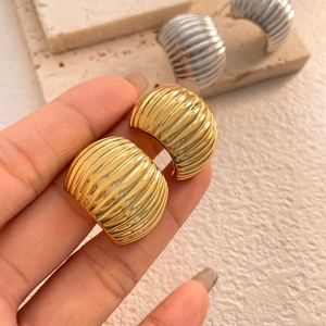 Macro shot of gold and silver C-shaped chunky ribbed metal earrings with metallic texture