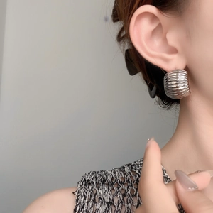 Detail shot of silver C-shaped chunky earrings featuring a textured ribbed metallic finish