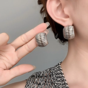 Close-up of silver C-shaped hoop earrings with dense wavy texture on a model