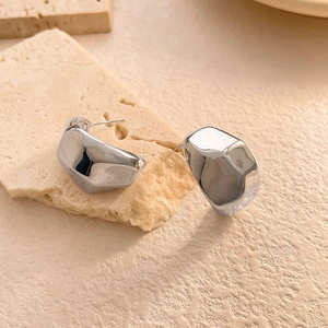 Gros plan détaillé de boucles d'oreilles géométriques argentées au fini miroir poli