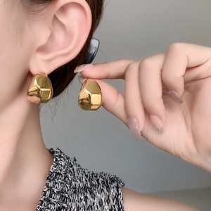 Gros plan de boucles d'oreilles créoles dorées épaisses avec finition miroir polie