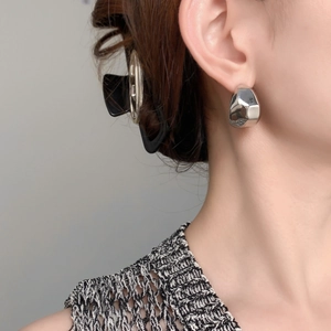 Gros plan de boucles d'oreilles créoles en argent poli sur un mannequin au style minimaliste