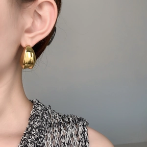 Boucles d'oreilles croissants dorées sur mannequin avec fini miroir métallique brillant