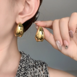 Gros plan de boucles d'oreilles gouttes dorées avec finition miroir sur mannequin