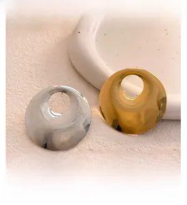 Macro view of minimalist circular mirror-finish stud earrings in gold and silver