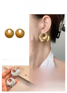 Close-up of modern hollow round geometric stud earrings in polished gold and silver finishes