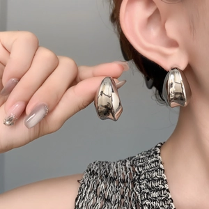 Gros plan de boucles d'oreilles goutte argentées polies avec finition miroir moderne