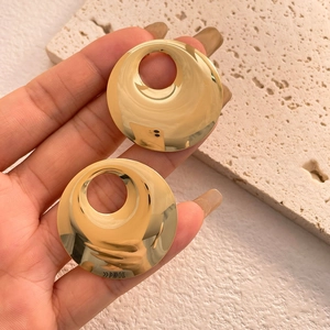 Macro detail of large hollow circular earrings with high-polish mirror gold finish