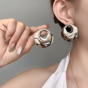 Macro shot of large polished silver hollow round earrings showing mirror-like finish