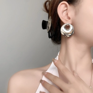 Minimalist large hollow round mirror finish silver metal earrings worn by a model