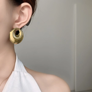 Close-up of chunky gold geometric circle earrings worn on model for high-shine look