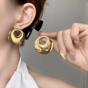 Detailed view of large gold circular earrings with a polished mirror finish and hollow center