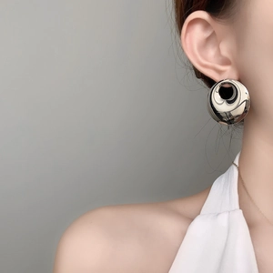 Detail of large multi-layer silver circular metal stud earring on a model