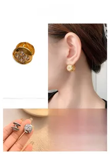 Macro shot of gold-plated flower hoop earrings with four brilliant zircon stones